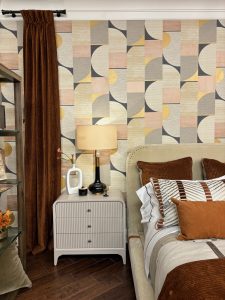 Bedroom with geometric wallpaper, brown curtains, and brown and terracotta bedding.